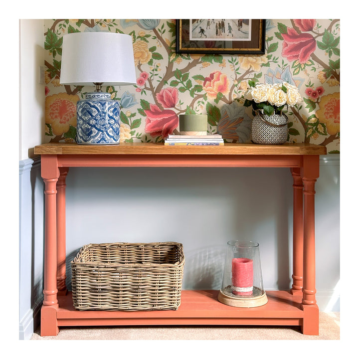 a pink console table decorated with an array of objects