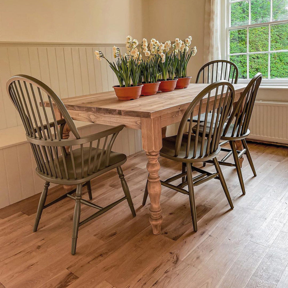 painted windsor dining chairs around a farmhouse style table in an english cottage
